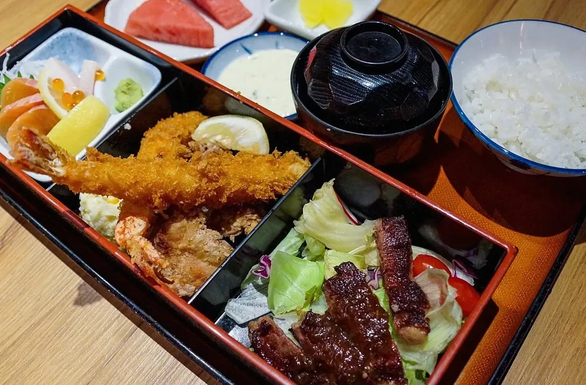 えびフライや刺身、焼いた肉、味噌汁、ご飯が入った定食